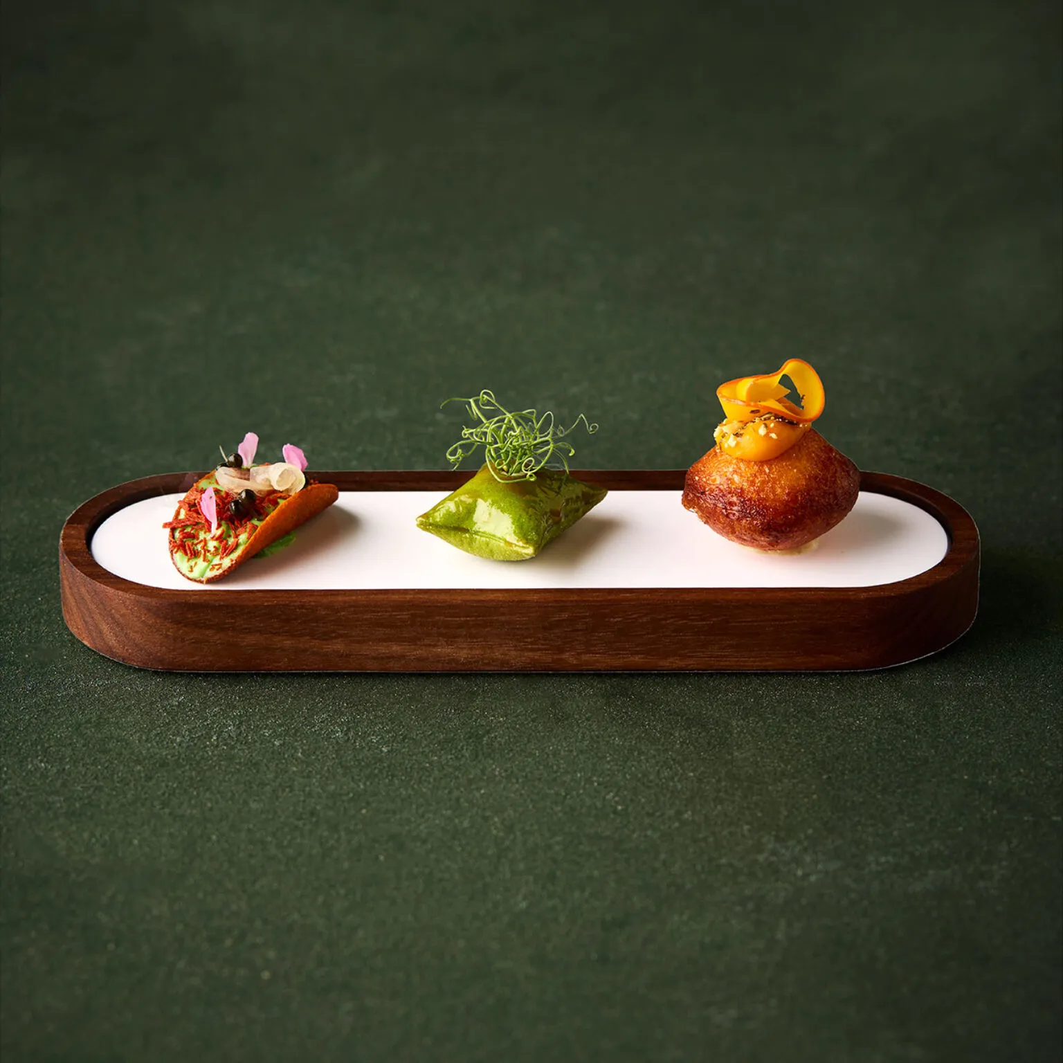 Amuse Gueule des 8-Gänge-Menüs Green Forest im Ammolite. Es sind drei feine Häppchen auf einer feinen Servierplatte aus Holz zu sehen.