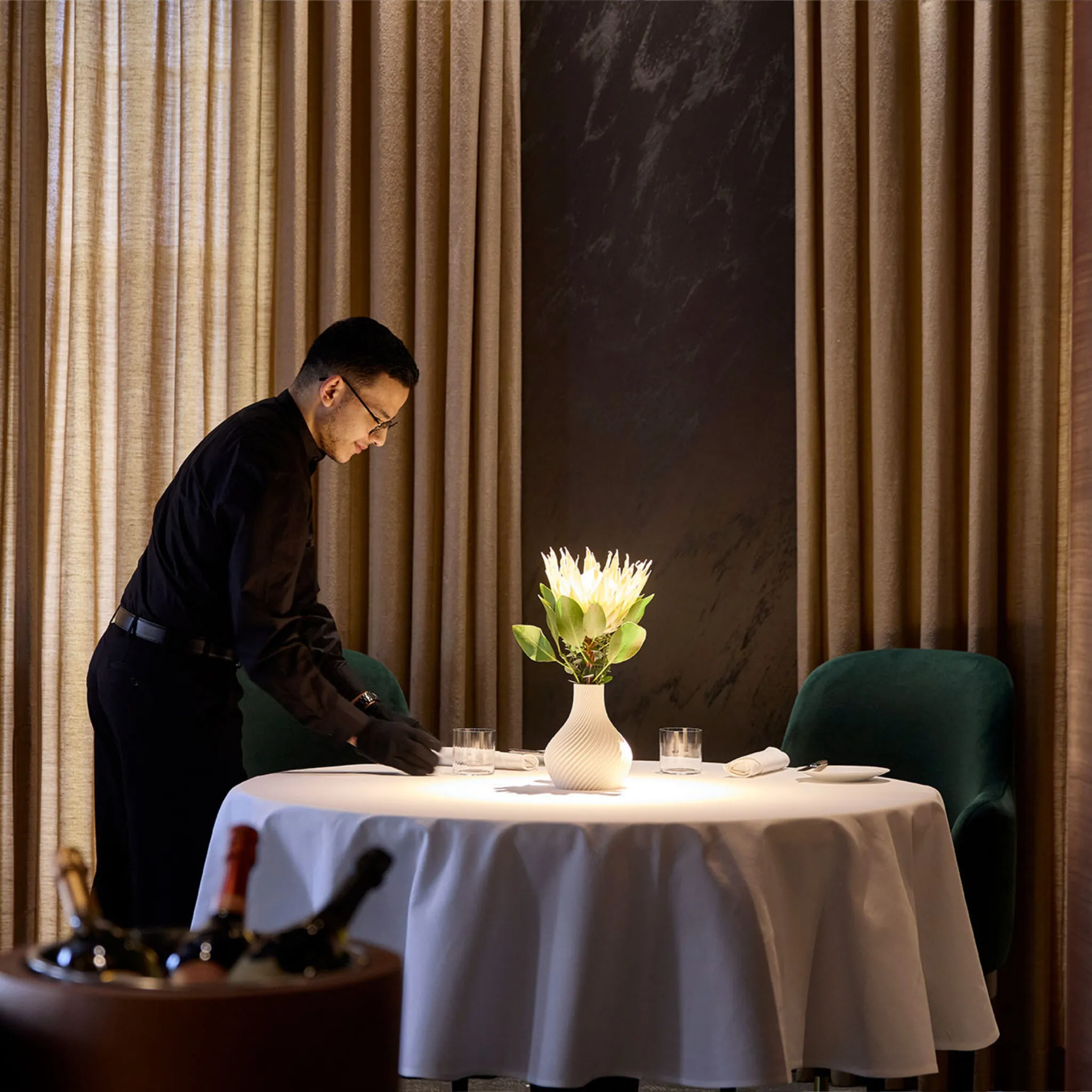 Ein Servicemitarbeiter des Ammolite – House of Light deckt einen Tisch im Restaurant ein.